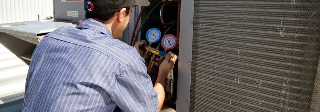 HVAC technician servicing a condenser unit in Burke Centre